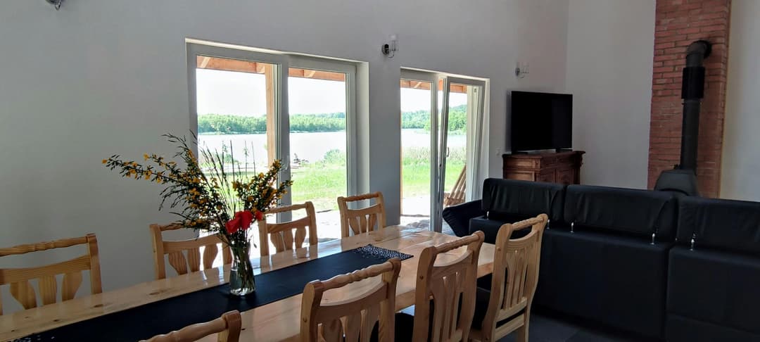 Jeziorosfera - Przestronny salon z dużym stołem i widokiem na jezioro